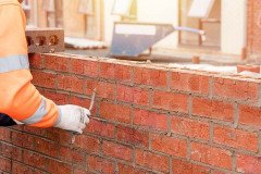 Bricklayer laying bricks on mortar on new residential house construction